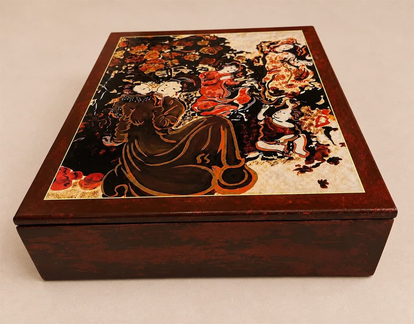 A completed lacquer presentation box: deep red-brown lacquered wood with a gold-bordered panel inlaid in the lid, reproducing one of Nguyễn Gia Trí's garden scenes in black, vermilion and eggshell