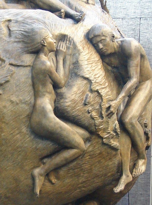 Detail of Where Cultures Meet: two bronze figures lying against the curve of the globe, one with a hand raised toward the other